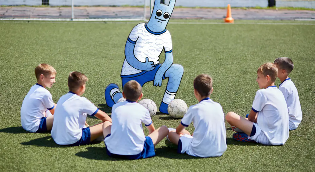 Das Hostsharing-Maskottchen steht wie ein Trainer vor einer Fußballjugendmannschaft.