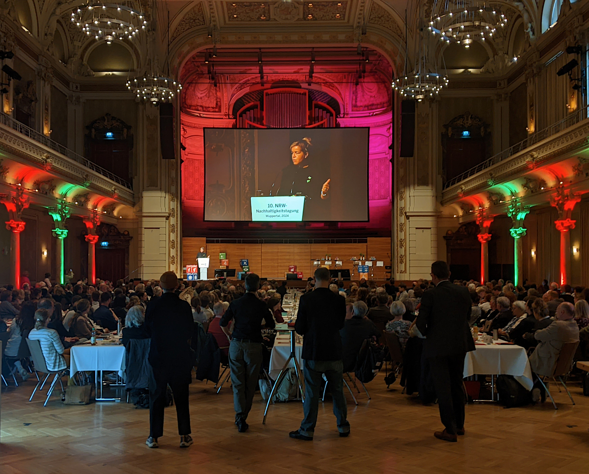 Großer Saal in der historischen Stadthalle Wuppertal. Auf der Bühne spricht Mona Neubaur.