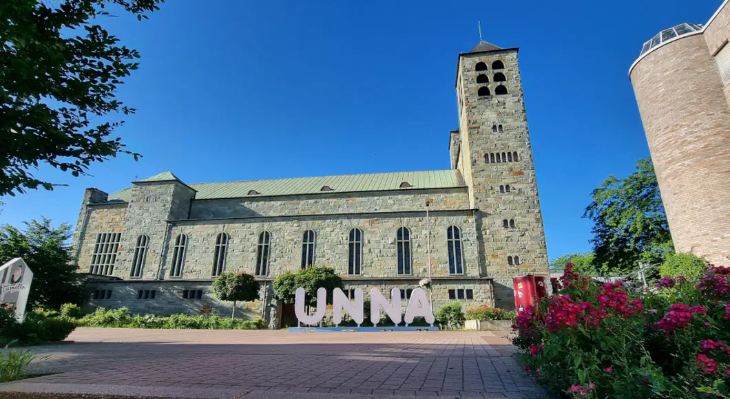 Schriftzug ›Unna‹ vor einer Kirche.